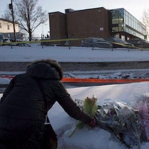 A woman places flowers near a mosque where a shooting left six people dead, Monday, January 30, 2017 in Quebec City. (Paul Chiasson/CP)