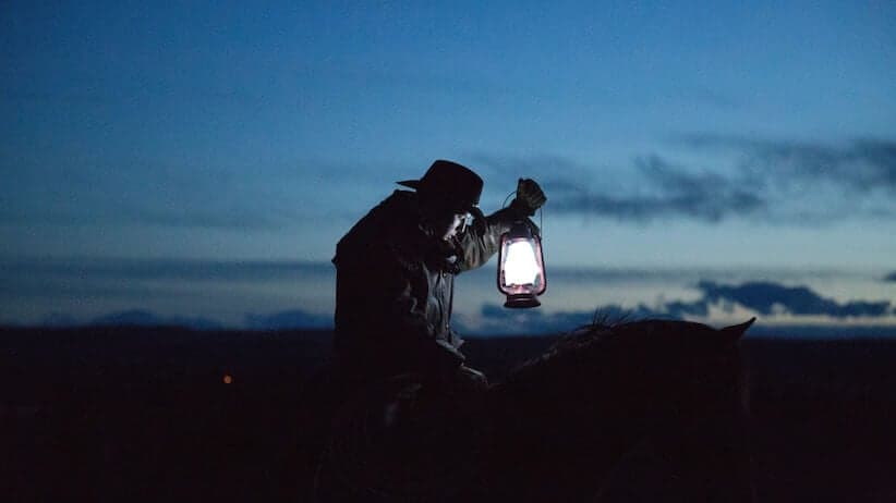 Cowboy on horse with lantern at dusk
