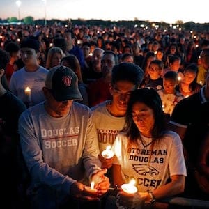 Jorge Zapata, Jr., center, a student at Marjory Stoneman Douglas High School, holds candles with his mother Lavinia Zapata, and father Jorge Zapata, Sr., during a candlelight vigil for the victims of the Wednesday shooting at the school, in Parkland, Fla., Thursday, Feb. 15, 2018. Nikolas Cruz, a former student, was charged with 17 counts of premeditated murder on Thursday. (AP Photo/Gerald Herbert)
