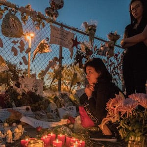 MARJORY STONEMAN DOUGLAS HIGH SCHOOL, PARKLAND, FLORIDA. 02/25/2018
A mourner sits by candles at a memorial tribute outside the school.
On February 14, 2018, a former school Stoneman Douglas student Nikolas Cruz entered the school at 2.30pm and proceeded to kill 3 teachers and 14 school children in a 7 minute shooting spree. Marjory Stoneman Douglas High School is located in Parkland, Florida, in the Miami metropolitan area. It is a part of the Broward County Public School district, and it is the only public high school in Parkland.
Photo by Giles Clarke/Getty Images