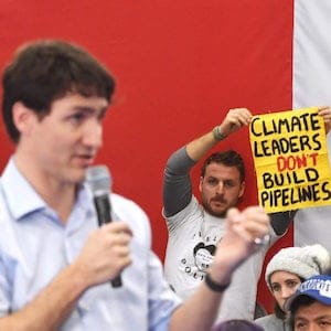 Protesters hold up signs as Prime Minister Justin Trudeau speaks at a public town hall in Nanaimo, B.C., on Friday, February 2, 2018.
(Jonathan Hayward/CP)