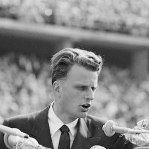 FILE - In this June 27, 1954 file photo, Evangelist Billy Graham speaks to over 100,000 Berliners at the Olympic Stadium in Berlin, Germany. Graham, who died Wednesday, Feb. 21, 2018, at his home in North Carolina's mountains at age 99, reached hundreds of millions of listeners around the world with his rallies and his pioneering use of television. Graham's body will be brought to his hometown of Charlotte on Saturday, Feb. 24, as part of a procession expected to draw crowds of well-wishers. (AP Photo/Werner Kreusch, File)