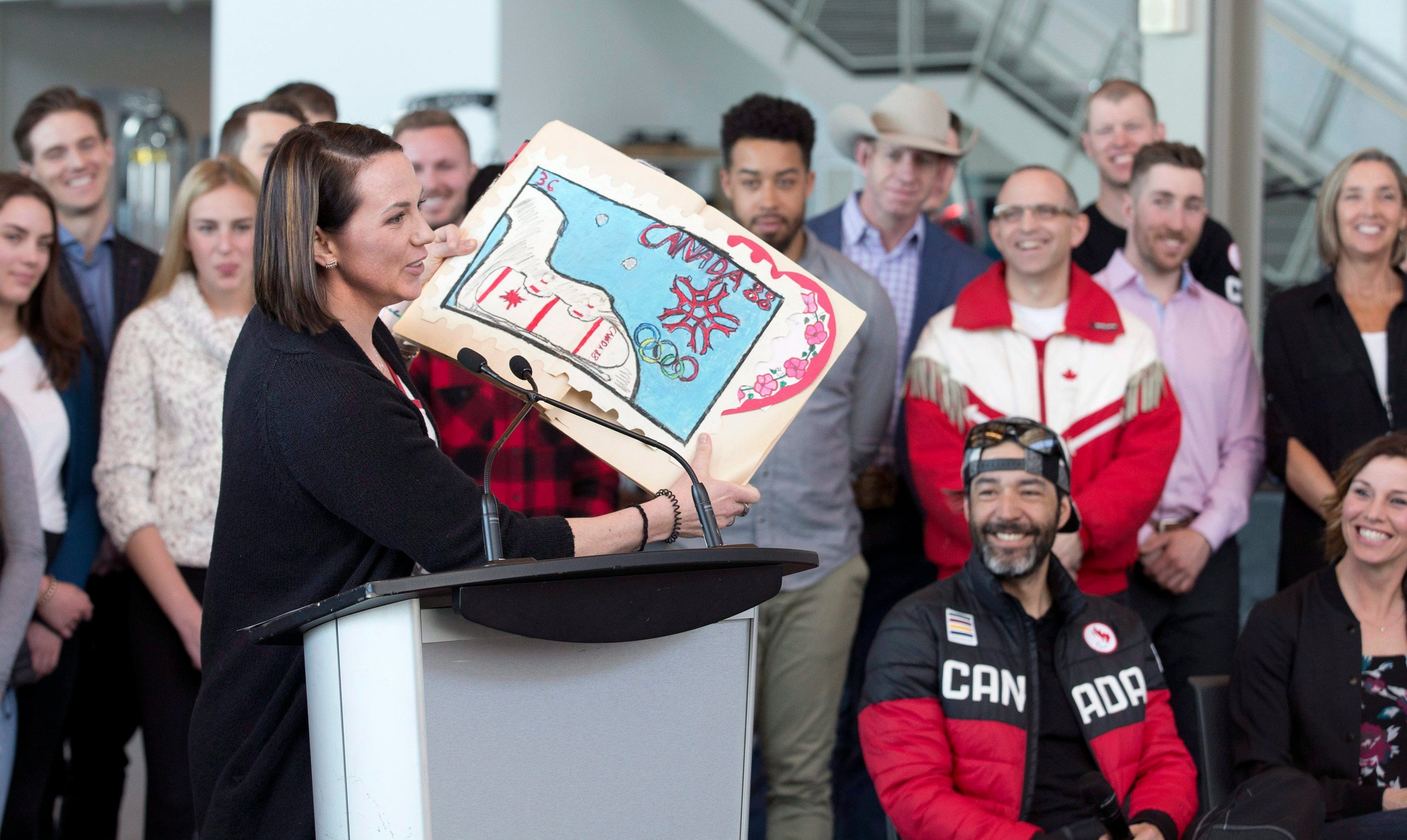 Former Olympic bobsledder Helen Upperton speaks and shows a poster that she made as a child for the 1988 Calgary winter games as athletes hold a press conference to encourage the city of Calgary to continue a Winter Olympic bid for 2026 in Calgary, Alta. on Friday, Apr. 13, 2018. (THE CANADIAN PRESS/Larry MacDougal)