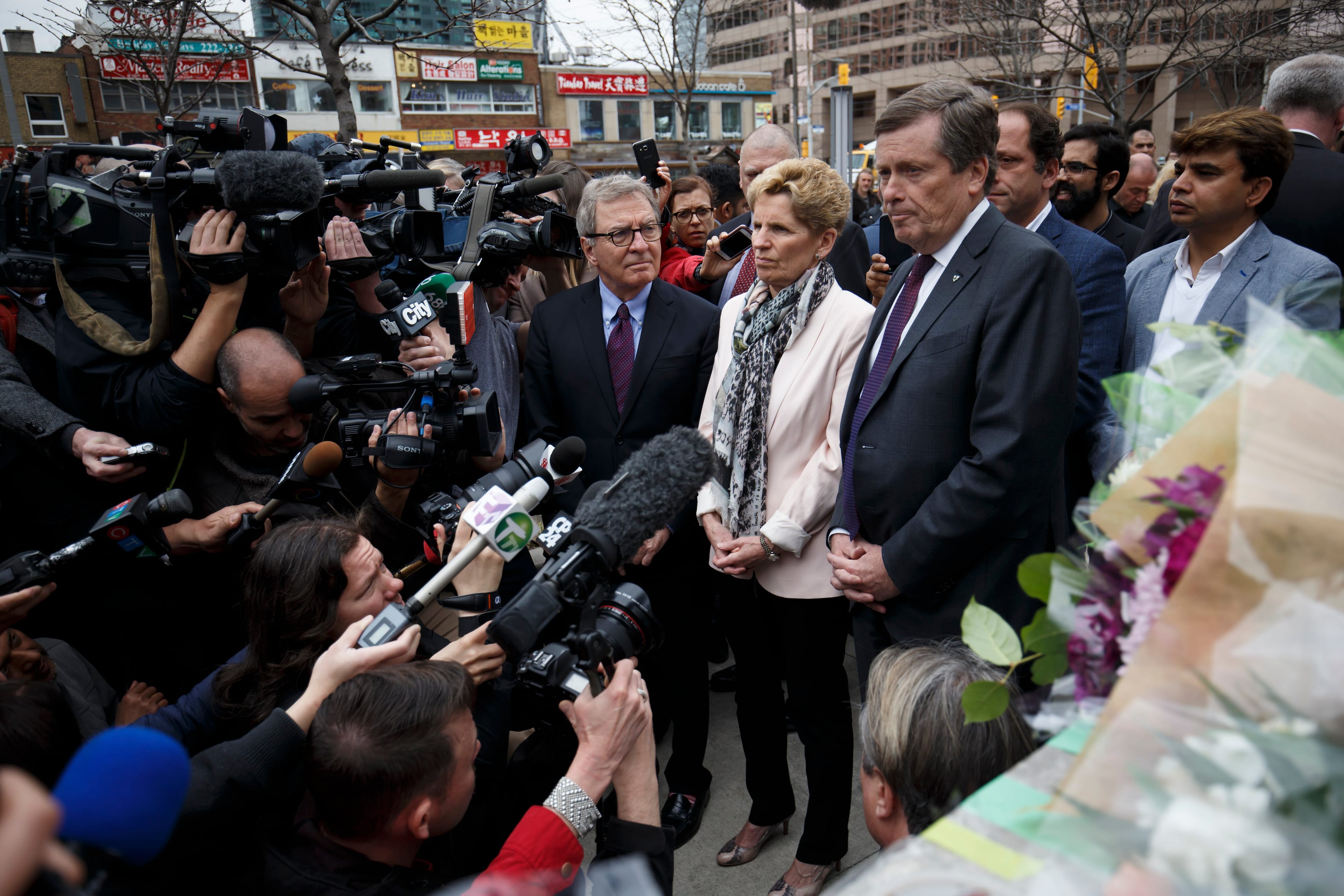 TORONTO, ON - APRIL 24: Ontario Premier Kathleen Wynne, middle, and Toronto Mayor John Tory, right, visit a memorial for victims of the mass killing on Yonge St. at Finch Ave. on April 24, 2018 in Toronto, Canada. A suspect identified as Alek Minassian, 25, is in custody after a driver in a white rental van drove into multiple pedestrians, killing 10 and injuring at least 16. (Photo by Cole Burston/Getty Images)