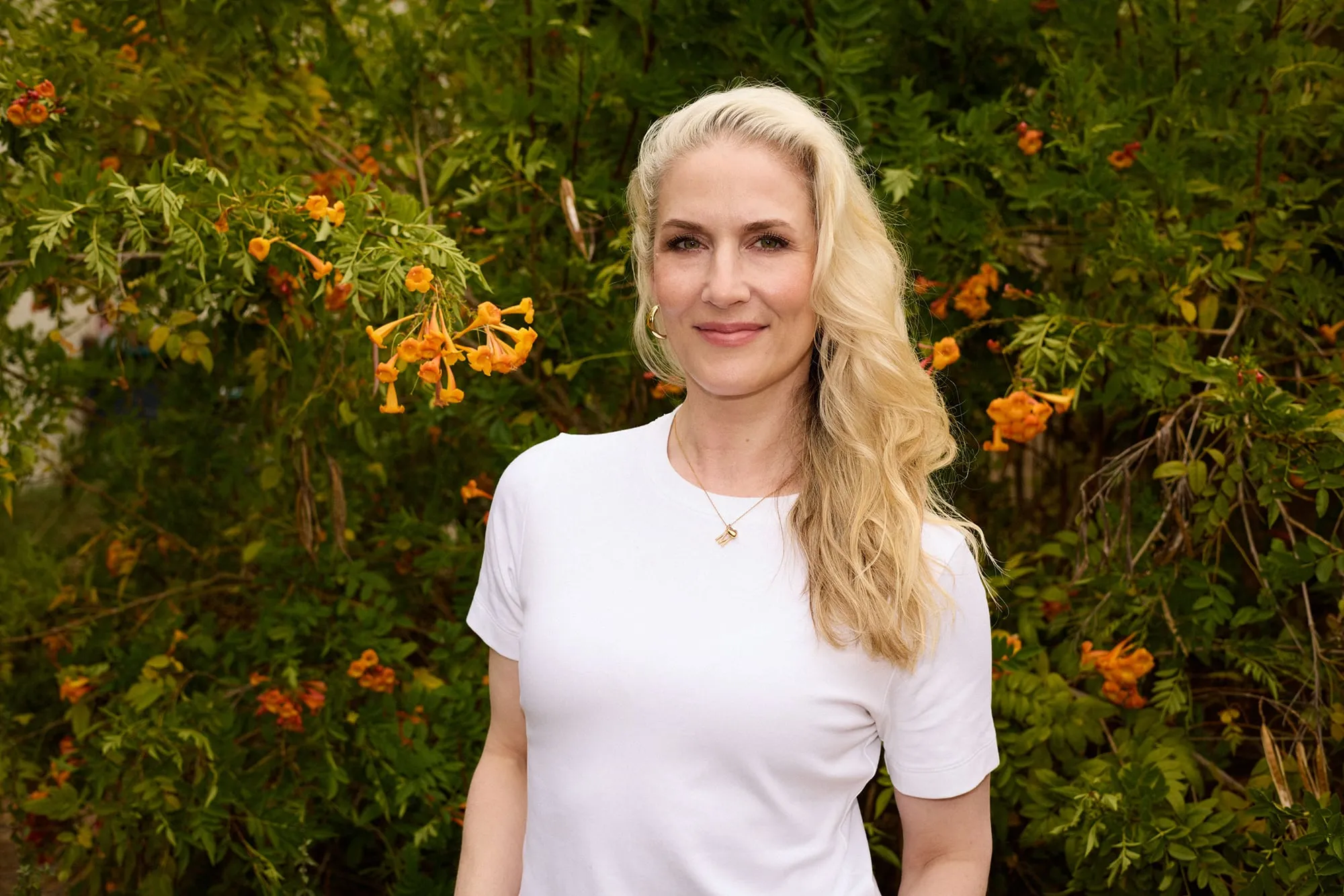 Alicia Read stands smiling in a white t-shirt with long blonde hair