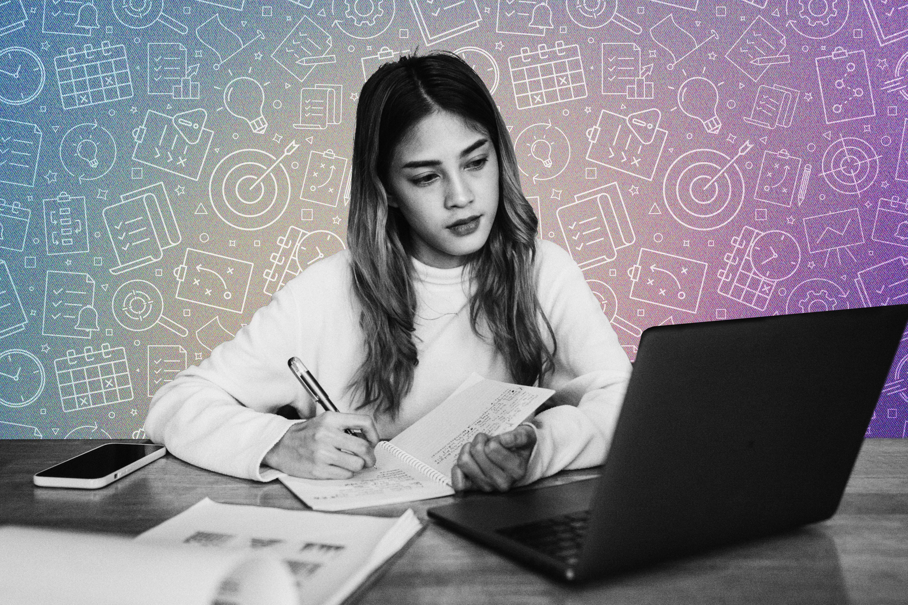 A student looking at a computer and writing in a notebook