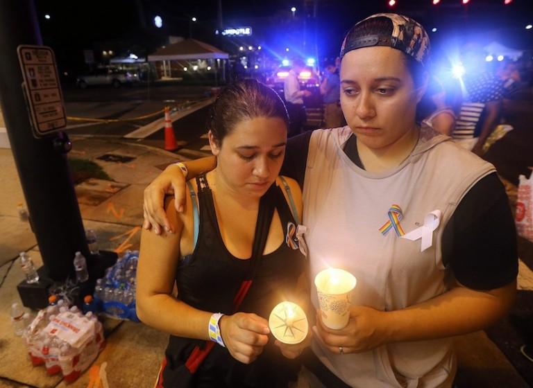 <p>Sonia, left, and Andrea Parra, who said they lost five friends in the Pulse nightclub shooting and have not heard from seven others, hold candles on the street corner near the Pulse holding their own vigil Sunday night in Orlando, Fla.,  June 12, 2016. (Curtis Compton/Atlanta Journal-Constitution via AP)</p>
