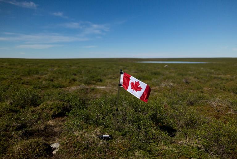 <p>Meagan Campbell plants a flag and leaves a geocache at the exact centre of Canada in Nunavut, Canada. (Photograph by Nick Iwanyshyn)</p>

