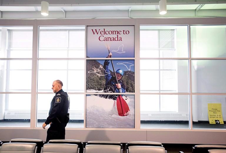 <p>A Canadian Border Services agent walks past a welcoming sign at Gate 521 at Pearson International Airport in Toronto. (Darren Calabrese/CP)</p>
