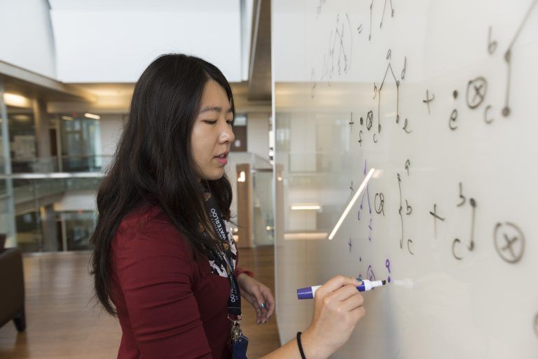 University of Waterloo student working on an equation on a whiteboard