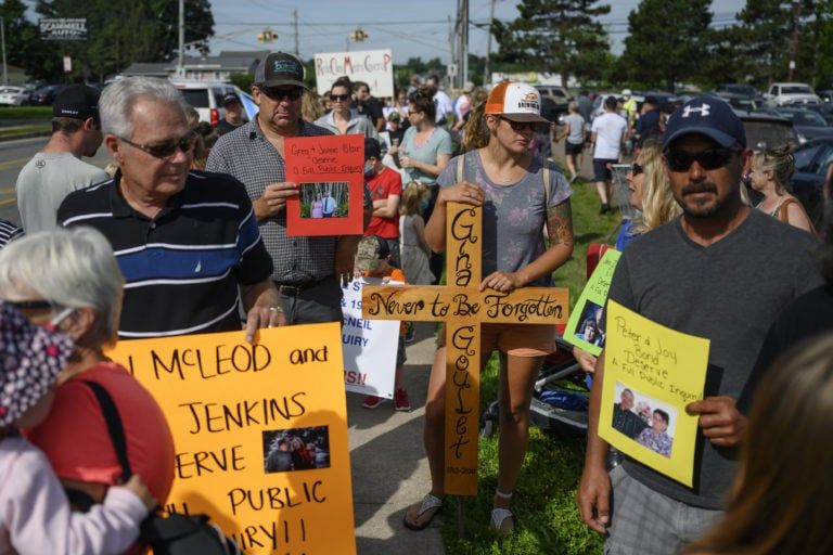 Dan Jenkins, left, holds a sign with his daughter and son-in-law’s names. While Amelia Butler, centre, carries a cross with her slain mother's name, Gina Goulet, as family members of victims gather for a march in Bible Hill, N.S. demanding a public inquiry into the RCMP's handling of Canada's deadliest rampage throughout rural Nova Scotia in April. (Photograph by Darren Calabrese)