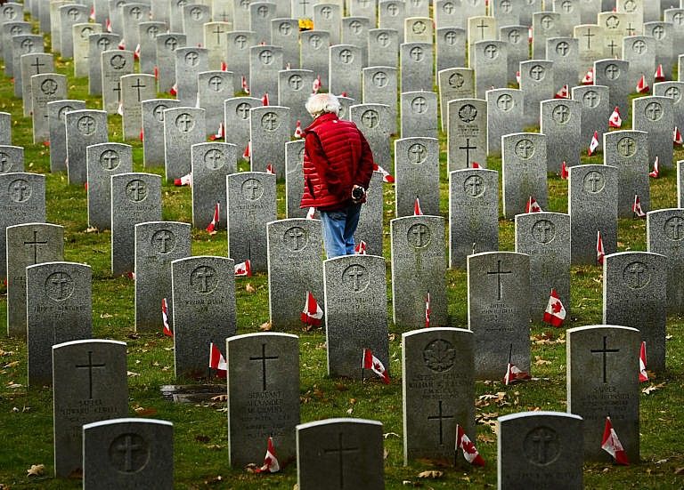 George McMenemy, 72, walks through the field of honour for fallen Canadian military war veterans at the Woodland Cemetery on Remembrance Day during the COVID-19 pandemic in Burlington, Ontario, Wednesday, Nov. 11, 2020. (Nathan Denette/CP)