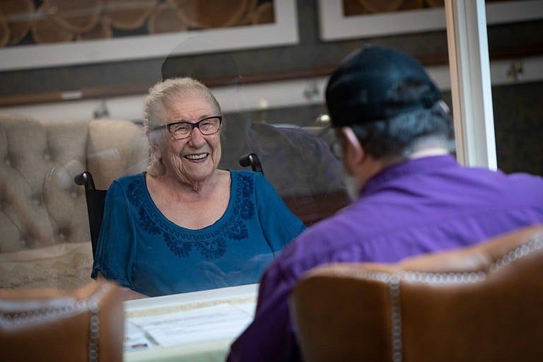 Ivy Metz, 86, smiles at her son Nick Metz as they visit separated by a plexiglass barrier at Lynn Valley Care Centre, in North Vancouver, on Friday, July 17, 2020. Visitors, who are screened on arrival, can now schedule to meet in a designated area with a physical barrier, however they aren't allowed to touch, hug or kiss. The seniors care home, which is now COVID-19 free, recorded Canada's first death from the virus on March 8. THE CANADIAN PRESS/Darryl Dyck