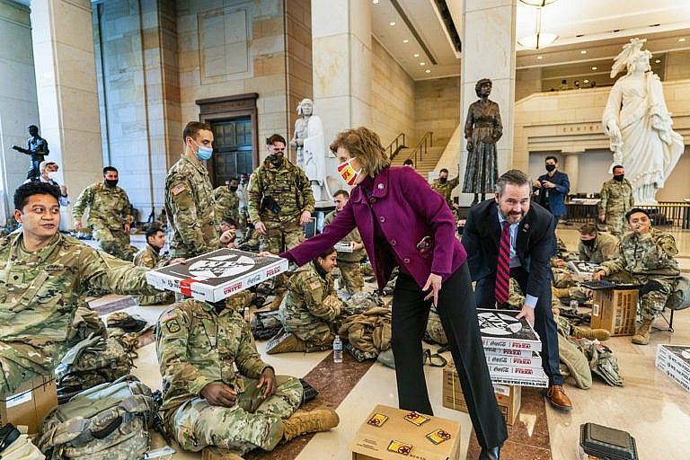 Rep. Vicky Hartzler, R-Mo., and Rep. Michael Waltz, R-Fla., hand pizzas to members of the National Guard gathered at the Capitol Visitor Center, Wednesday, Jan. 13, 2021, in Washington. as the House of Representatives continues with its fast-moving House vote to impeach President Donald Trump, a week after a mob of Trump supporters stormed the U.S. Capitol. (Manuel Balce Ceneta/AP/CP)