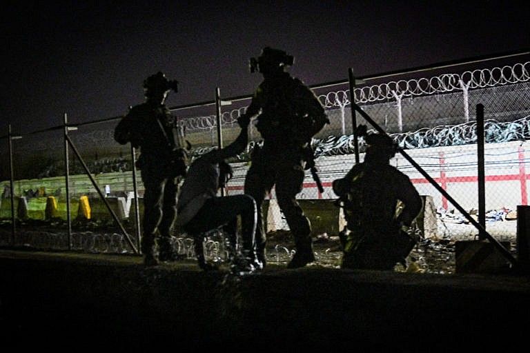 In this picture taken in the late hours on August 22, 2021 British and Canadian soldiers help an Afghan climb up on the wall of a canal as he with others wait near the foreign military-controlled part of the airport in Kabul, hoping to flee the country following the Taliban's military takeover of Afghanistan. (Wakil Kohsar/AFP/Getty Images)