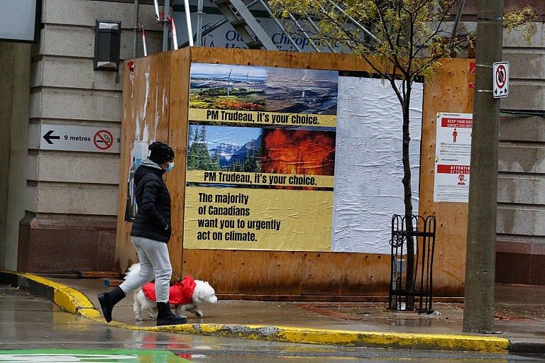 A pedestrian walks by a poster installation in Ottawa on Oct. 31, 2021 (CP)