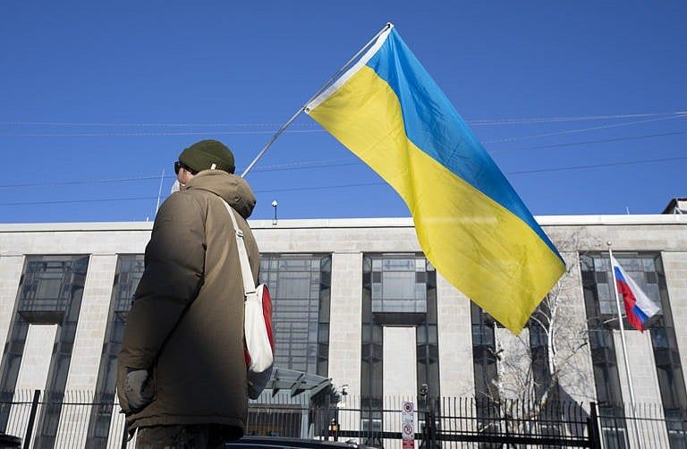 A pro-Ukrainian supporter waves the country's flag outside the Russian embassy on Feb. 24, 2022 in Ottawa (Adrian Wyld/CP)