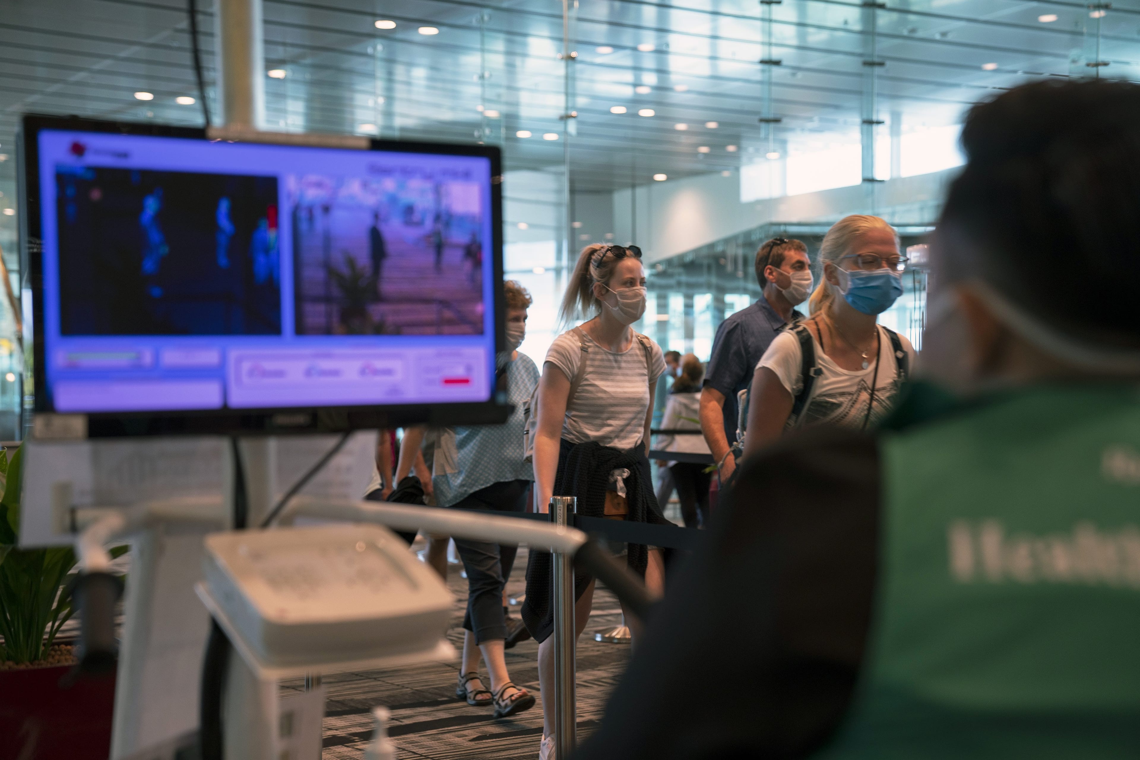 Arriving passengers wearing protective masks walk past a temperature screening point at Singapore Changi Airport in Singapore, on March 17, 2020 (Wei Leng Tay/Bloomberg via Getty Images)