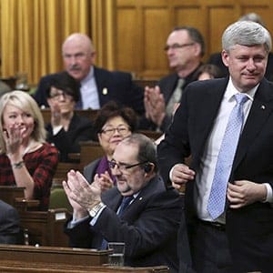 Canada's Prime Minister Stephen Harper stands to vote in the House of Commons on Parliament Hill in Ottawa March 30, 2015. Parliamentarians voted to expand Canada's military mission against Islamic State by launching air strikes against the militants' safe havens in Syria as well as Iraq. Chris Wattie/Reuters