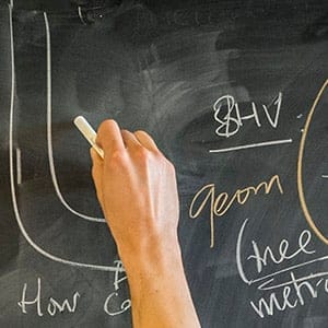 A mathematician uses Hagoromo chalk to write on a chalkboard. (Photograph by Satyan L. Devadoss)