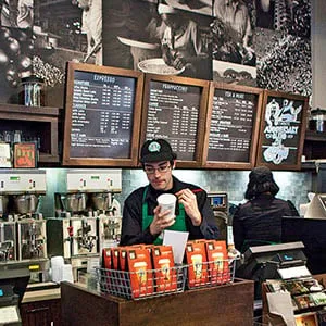 A customer purchases coffee at a newly redesigned Starbucks store in New York City, on Friday, October 29, 2010. Starbucks has committed to have all of its new company-owned stores LEED certified by the end of 2010. (Ramin Talaie/Corbis)