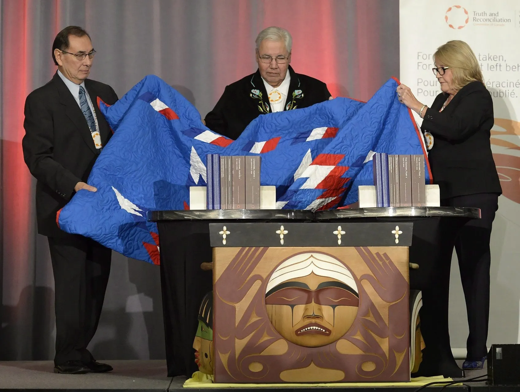 Justice Murray Sinclair (centre) and Commissioners Chief Wilton Littlechild (left) and Marie Wilson pull back a blanket to unveil the Final Report of the Truth and Reconciliation Commission of Canada on the history of Canada's residential school system, in Ottawa on Tuesday, Dec. 15, 2015. (Adrian Wyld/CP)