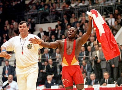 Referee announces Daniel Igali of Burnaby, B.C., Canada, as the winner of the 69 kg final against Lincoln McIlravy of USA, in the 34th World Wrestling Freestyle Championships in Ankara on Sunday, Oct. 10, 1999. Igali waves a Canadian flag toward Turks applauding him. Igali defeated McIlravy 3-2 to win Canada's first gold medal in a wrestling world championships. (Burhan Ozbilici/AP)
