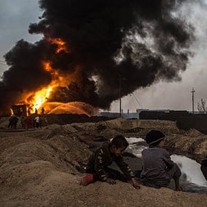 Young boys watch on as firefighters work to extinguish an oil well set on fire by fleeing ISIS members on November 9, 2016 in Al Qayyarah, Iraq. Many families have begun returning to their homes in recently liberated towns south of Mosul. Oil wells in the area that were set on fire by ISIS continue to burn blanketing the area in think clouds of smoke and oil. (Chris McGrath/Getty Images)