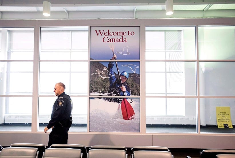 A Canadian Border Services agent walks past a welcoming sign at Gate 521 at Pearson International Airport in Toronto. (Darren Calabrese/CP)