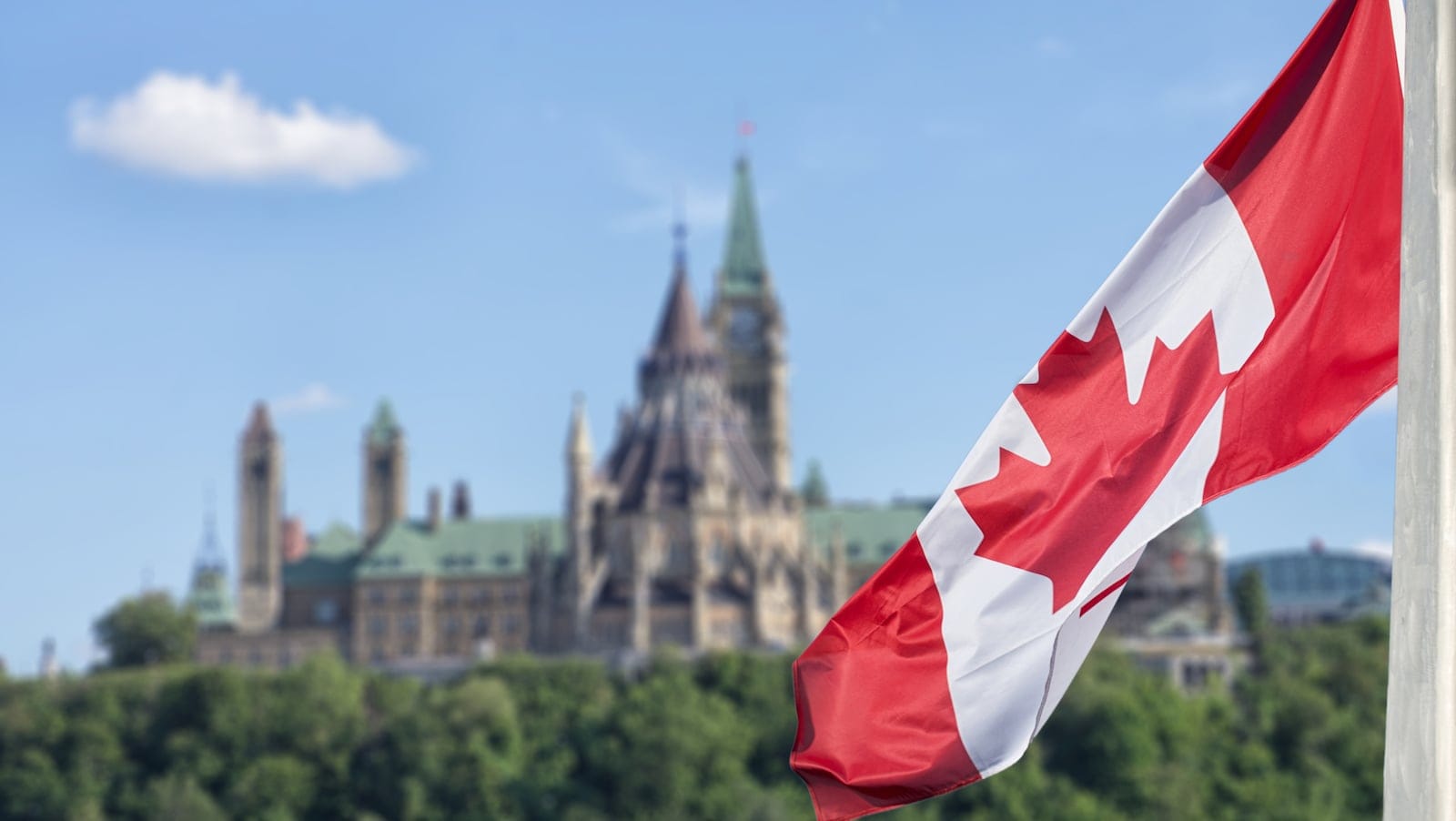 Canadian flag waving with Parliament Buildings hill and Library in the background