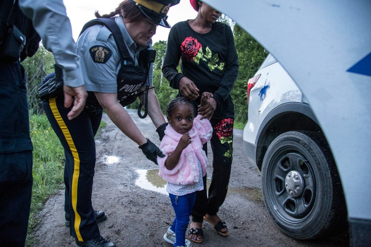 A woman and child being led to a police car