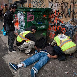 Staff members from the popup safe injection tent prepare the insect a man with Naloxone as he overdoses in a Downtown Eastside alley in Vancouver, British Columbia, November 18, 2016. (Rafal Gerszak)