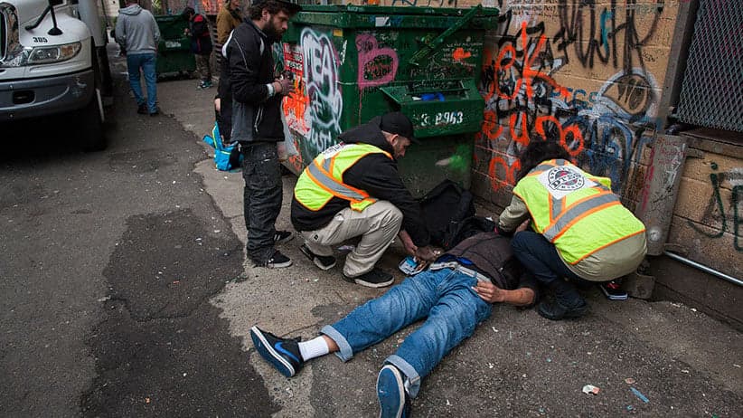 Public health workers injecting a man with naloxone