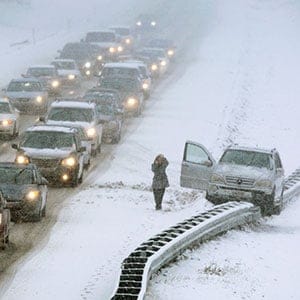 A woman uses a cell phone after climbing out of a vehicle that ended up on a guard rail in the median of Interstate 295 during a snow storm in Cumberland, Maine, Friday, Feb. 25, 2011. (AP Photo/Robert F. Bukaty)