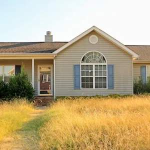 All too common scene of an unkempt, ranch style, home in the foreclosure process in a working class subdivision in the United States, with overgrown yard and bushes making it an eyesore to the neighborhood.