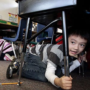Grade one student, six-year-old Joseph Kim, takes cover under his desk during an earthquake drill at Hollyburn Elementary School in West Vancouver, B.C., on Wednesday January 26, 2011. More than 400,000 British Columbians took part in the drill called "ShakeOut" simultaneously at schools and businesses across the province in the largest earthquake-preparedness program ever held in Canada. (Darryl Dyck/CP)
