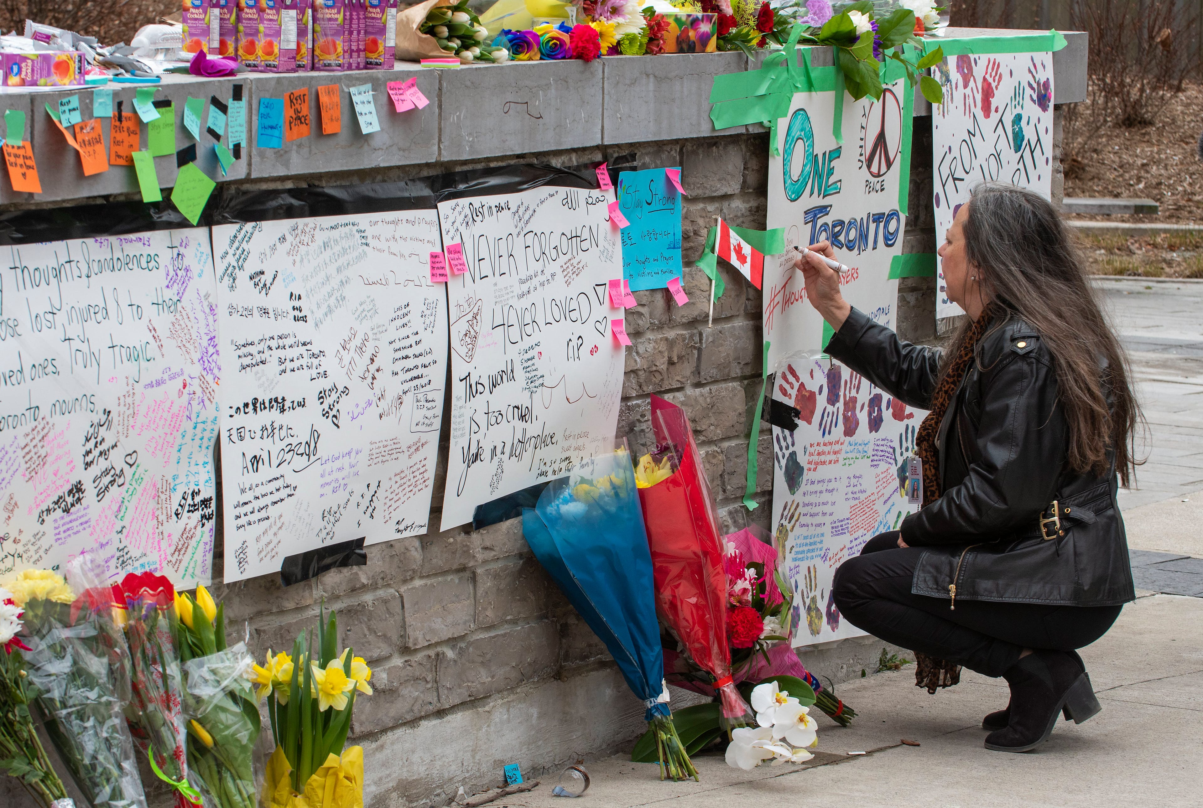 A woman writes a message at a makeshift memorial across the street from where a man in a rented van plowed into pedestrians on Yonge Street in northern Toronto, Canada, 24 April 2018. Ten people were killed and 15 injured on 23 April 2018, after a man driving a rented van mowed down pedestrians along a one-mile stretch of Yonge Street. EPA/WARREN TODA