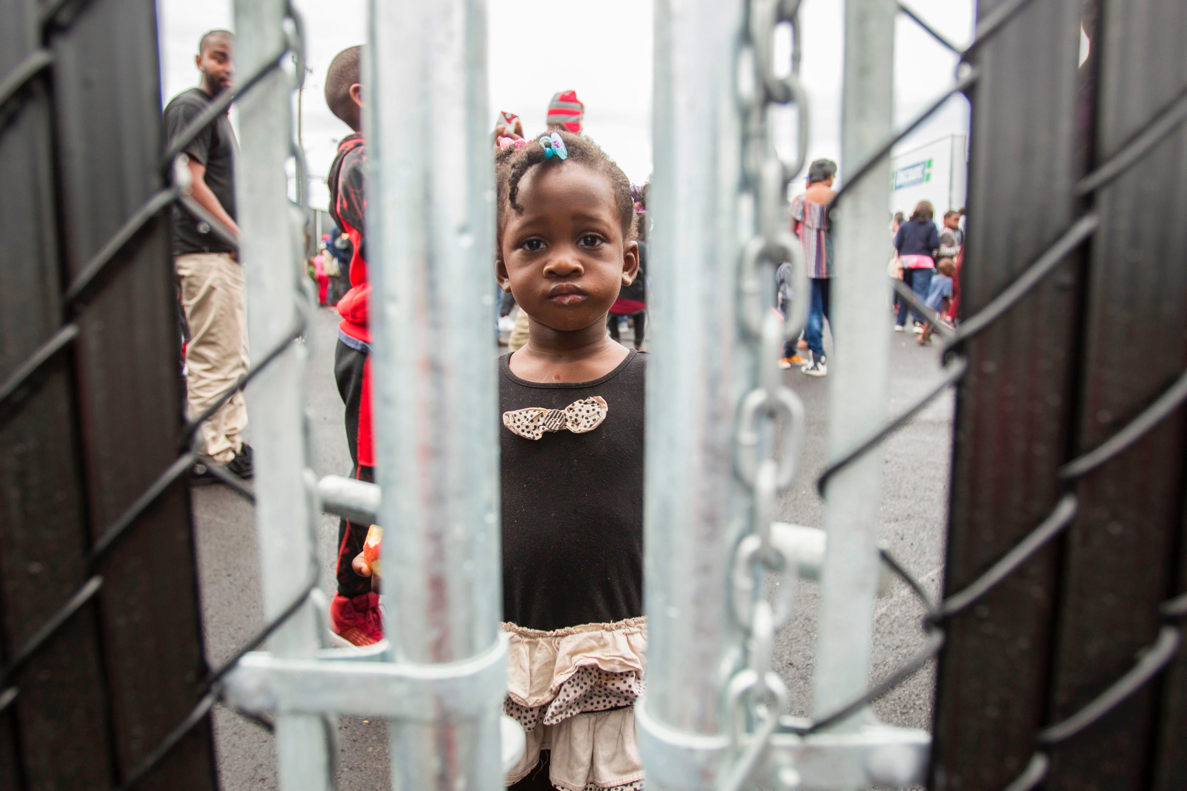 This girl and her family crossed the Canada/US border illegally to claim refugee status in Canada, looks through a fence at a temporary detention centre in Blackpool, Quebec, August 5, 2017. (Geoff Robins/AFP/Getty Images)
