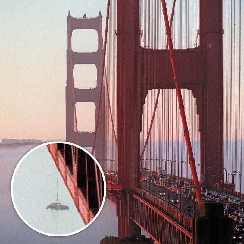 Morning rush hour traffic on the Golden Gate Bridge near Marin County in California is backed up as the shell of an old Volkswagen Beetle dangles from the railing of the bridge, Monday, Feb. 5, 2001, in San Francisco. In this photo, fog obstructs a view of the car as it hangs over the edge of the structure. Engineering students at the University of British Columbia said Monday they were responsible for tethering the shell of the car to the railing of bridge and then tossing it over the side. The stunt backed up rush-hour traffic as gawkers slowed to look at the dangling car. The car was cut loose at about 8:10 a.m. by the Golden Gate Bridge District, and it quickly sank as U.S. Coast Guard crews kept the area under the bridge clear. (AP Photo/Jakub Mosur)