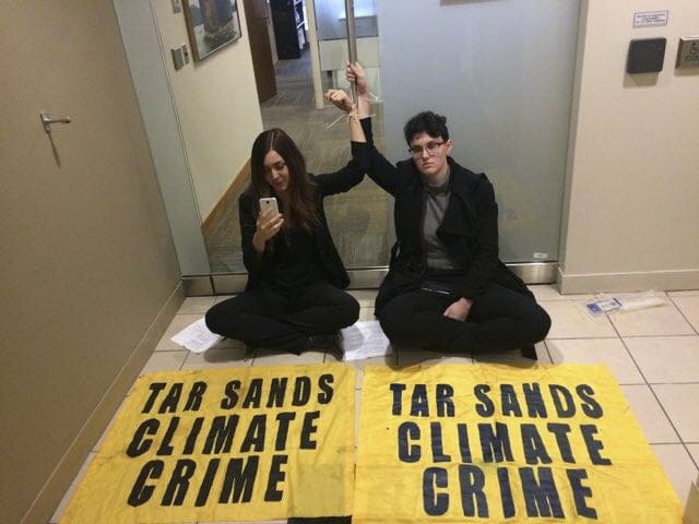 Climate Justice Edmonton protestors Anna Gerrard and Kate Jacobson sit zip-tied to the doors to Kinder Morgan in Calgary (Emma Jackson)