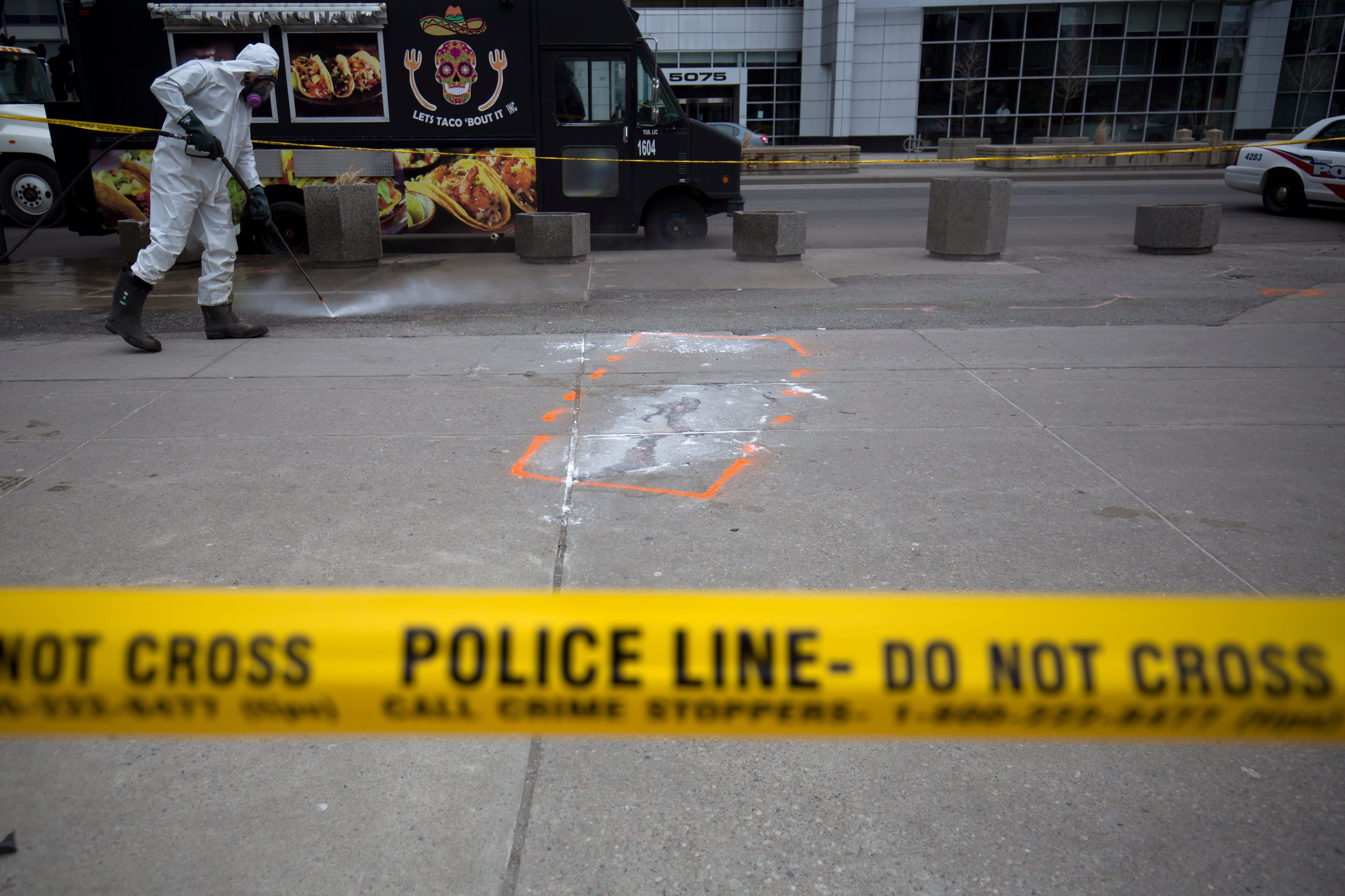 TORONTO, ON - APRIL 24: A hazmat worker scrubs the sidewalk of blood and debris near an outline of where a body laid after a mass killing on Yonge St. at Finch Ave. on April 24, 2018 in Toronto, Canada. A suspect identified as Alek Minassian, 25, is in custody after a driver in a white rental van drove into multiple pedestrians, killing 10 and injuring at least 16. (Photo by Cole Burston/Getty Images)