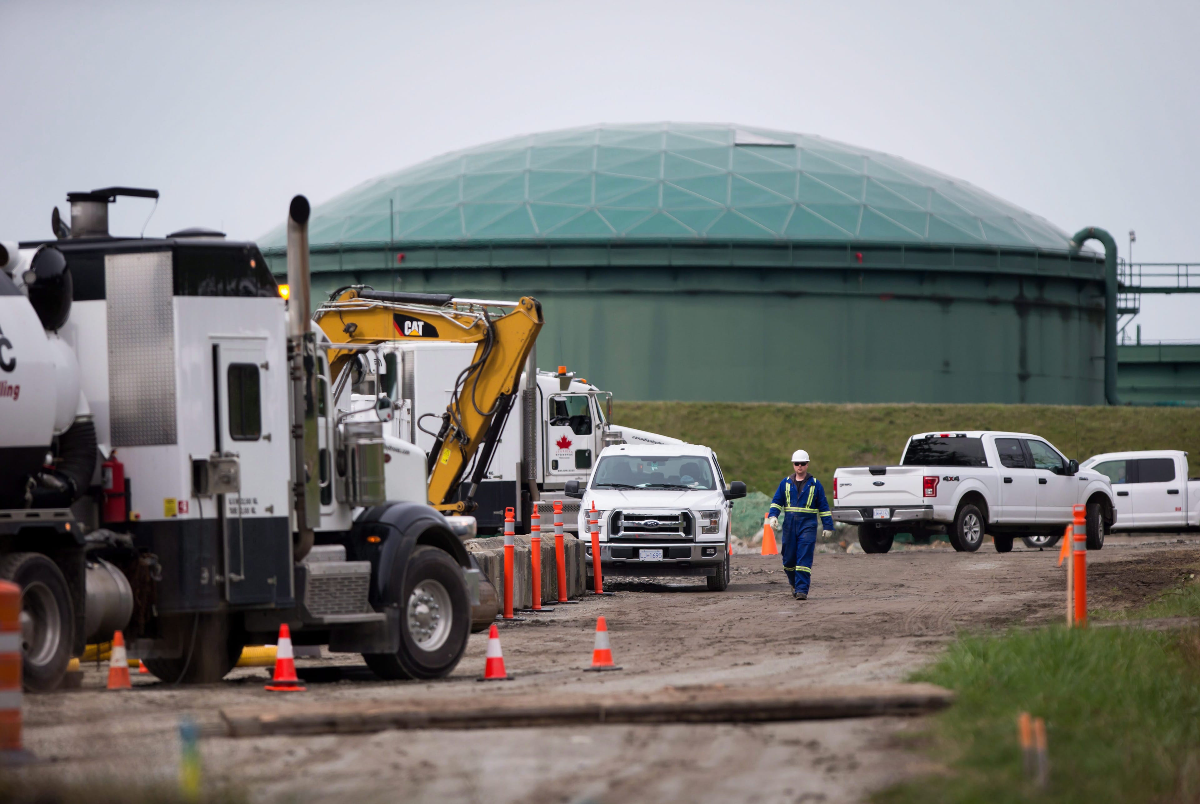A worker walks past heavy equipment as work continues at Kinder Morgan's facility in preparation for the expansion of the Trans Mountain Pipeline, in Burnaby, B.C., on Monday April 9, 2018. THE CANADIAN PRESS/Darryl Dyck