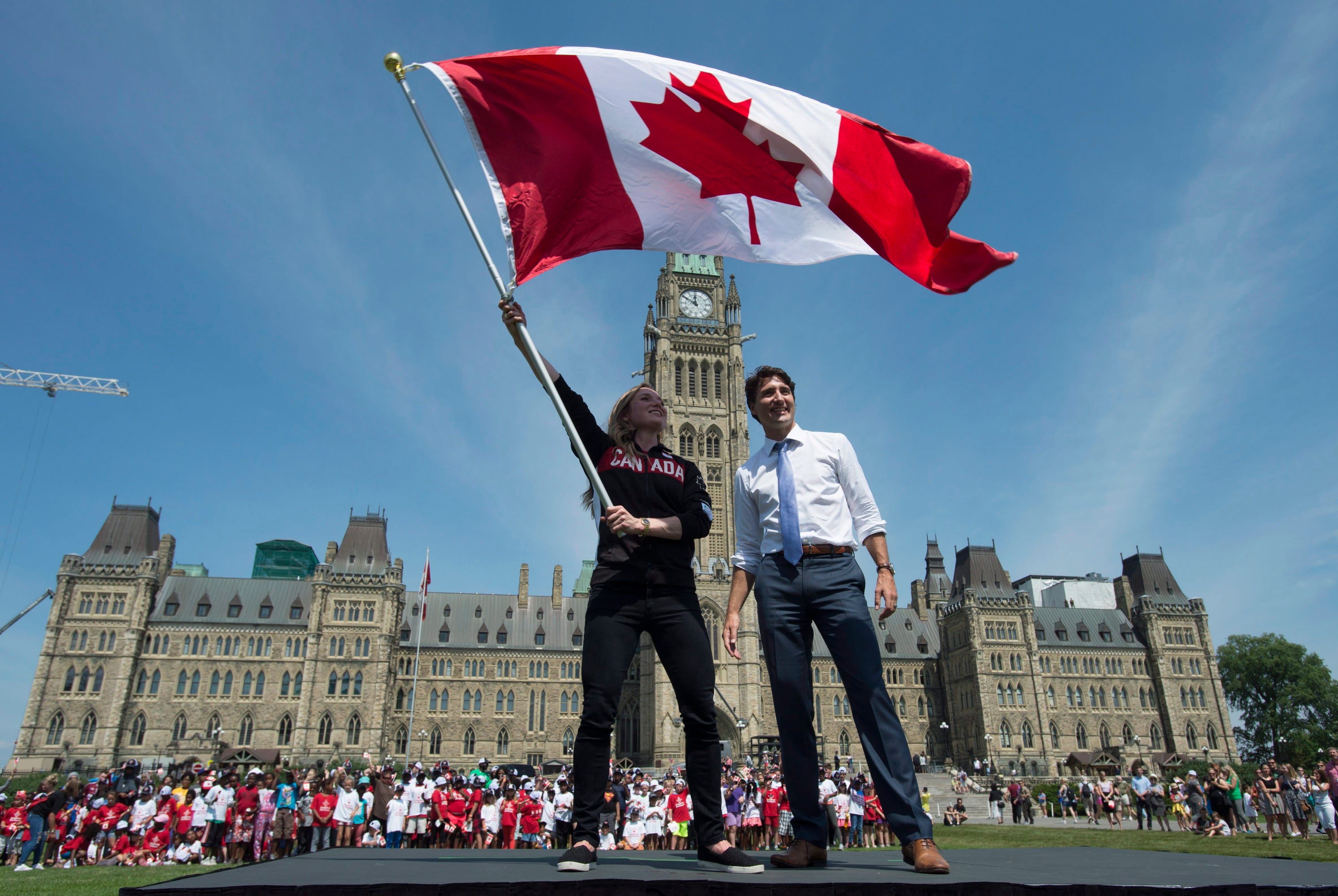 Canadian Prime Minister Justin Trudeau looks on as athlete Rosie MacLennan waves the Maple Leaf after being named as the flag bearer for the Summer Olympics on July 21, 2016 in Ottawa. (Adrian Wyld/CP)