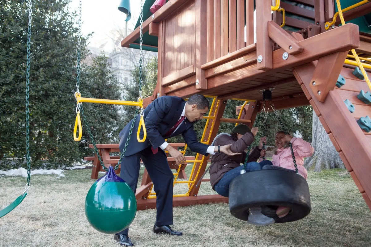 In this official White House photograph, President Barack Obama plays with daughters Malia and Sasha on the new playground swing-set. on the South Lawn of the White House, March 4, 2009. (Pete Souza/The White House)