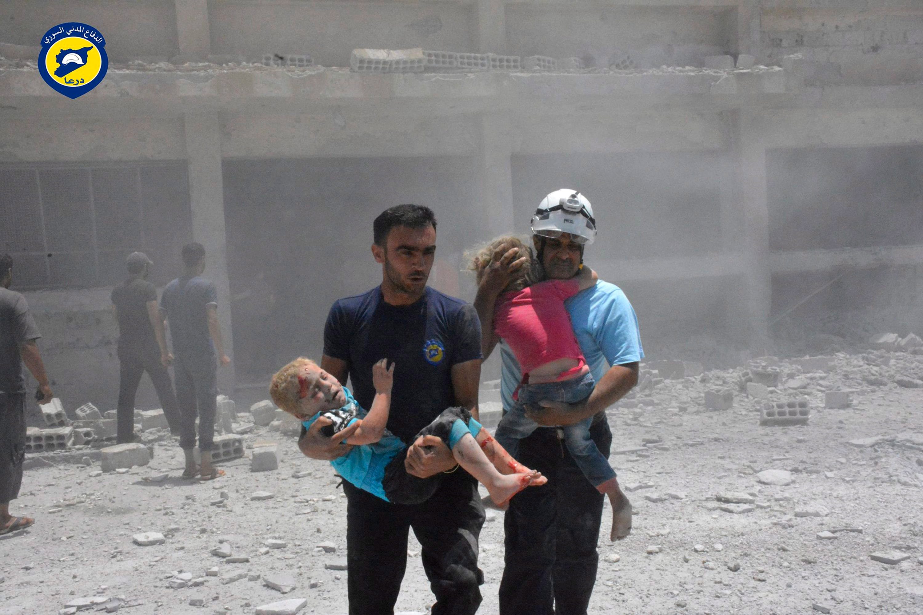 White Helmets carrying children after airstrikes hit a school in the western part of the southern Daraa in 2017 (Syrian Civil Defense White Helmets via AP, File)