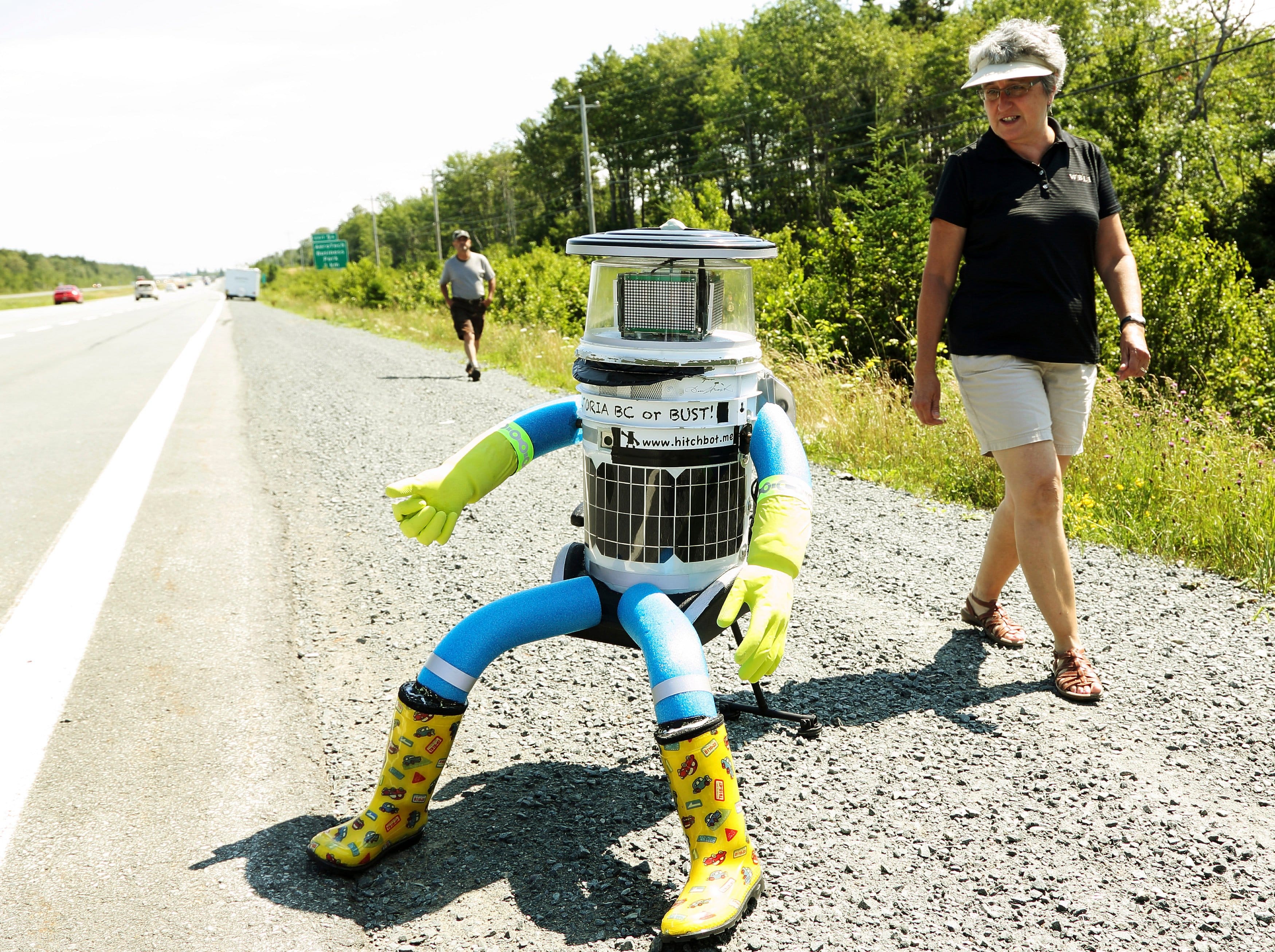 Anne Saulnier (R) and her husband Brian prepare to give a ride to the anthropomorphic robot named hitchBOT on Highway 102 outside of Halifax, Nova Scotia, July 27, 2014. The hitch hiking robot is part of a social experiment to see if strangers will help hitchBOT complete its 6,000 kilometer journey from Halifax to Victoria, British Columbia. (Paul Darrow/Reuters)