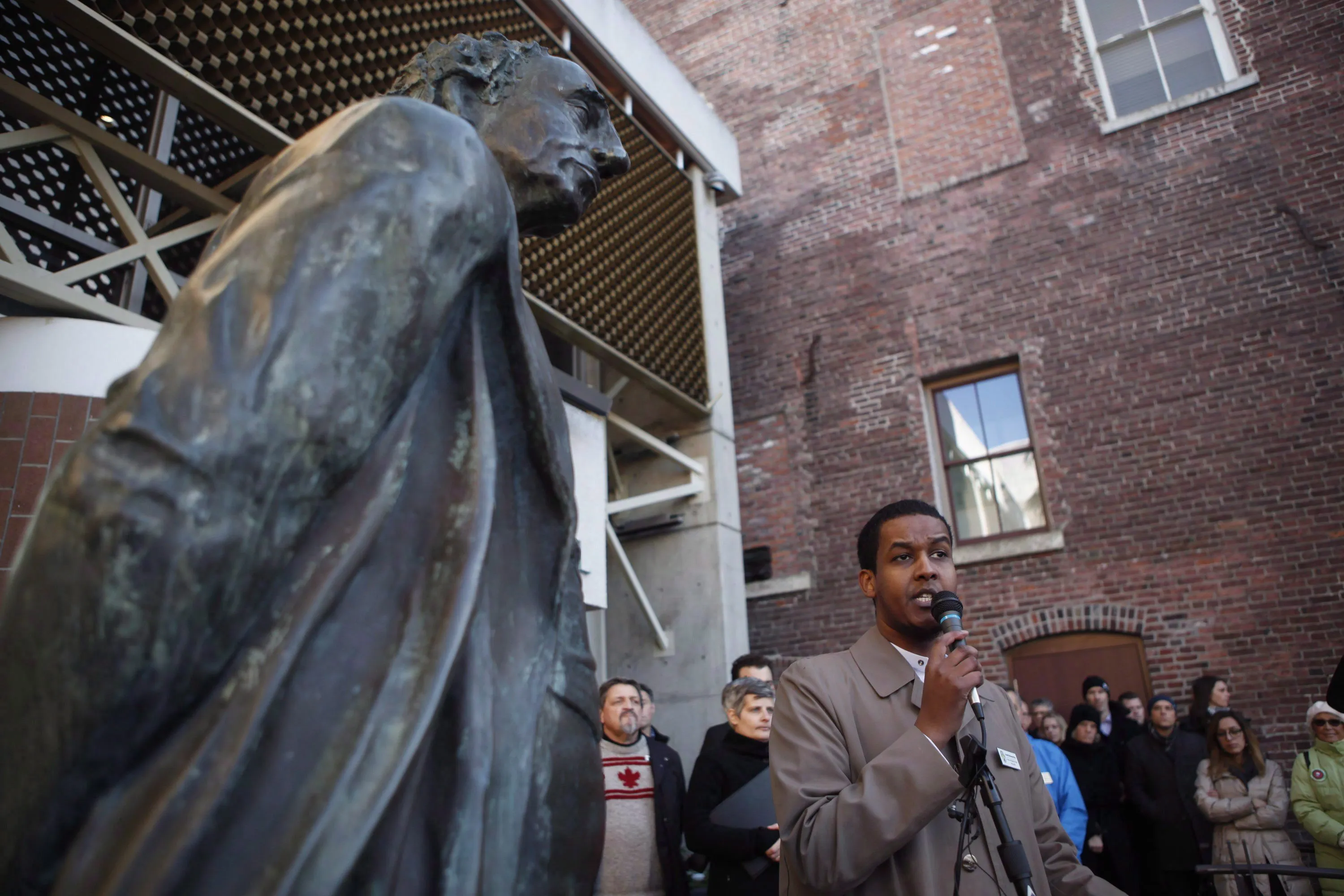 A statue of Sir John A. MacDonald overlooks the Imam at Masjid Al-Iman, Ismail Mohamed Nur, as he speaks to supporters and to the city of Victoria and the Muslim community during a vigil to honour the victims of the Quebec City mosque shooting in Victoria, B.C., on Jan. 31, 2017. The mayor of Victoria says a statue of Prime Minister John A. MacDonald will be removed from the front entrance to city hall as a gesture of reconciliation with First Nations. (Chad Hipolito/CP)