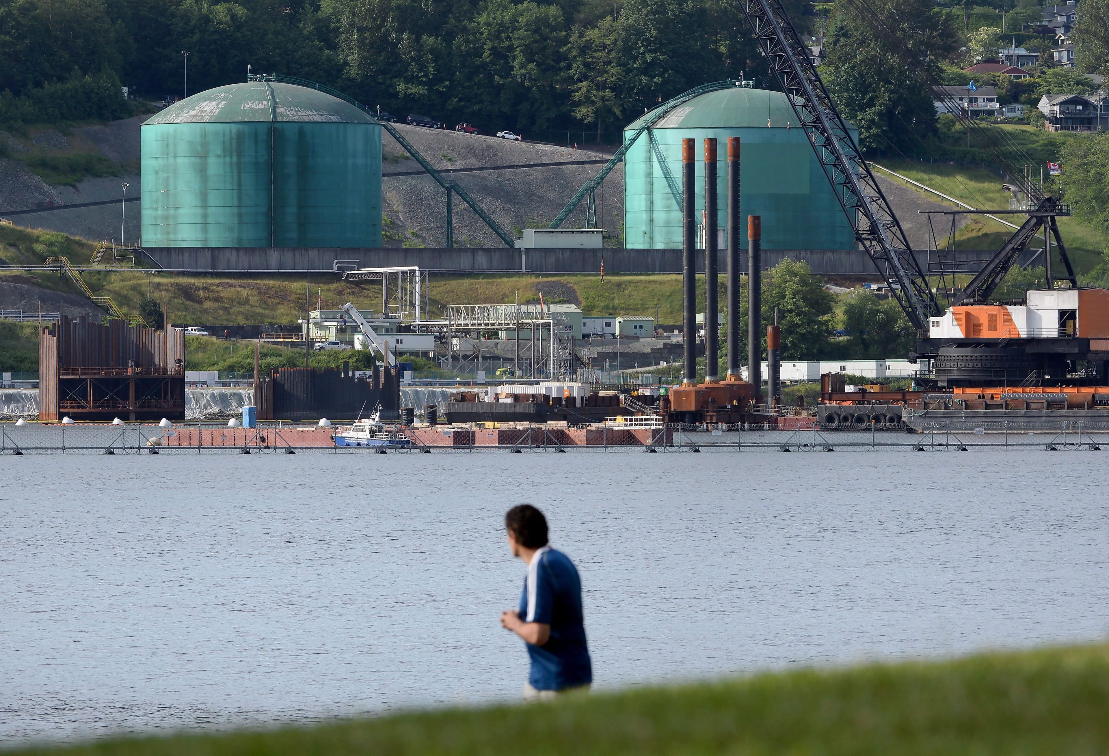 Kinder Morgan's Trans-Mountain marine terminal, located in Burnaby, B.C., is pictured across the water as a person walks through Cates Park in North Vancouver, B.C., on Tuesday, May 29, 2018. THE CANADIAN PRESS Jonathan Hayward