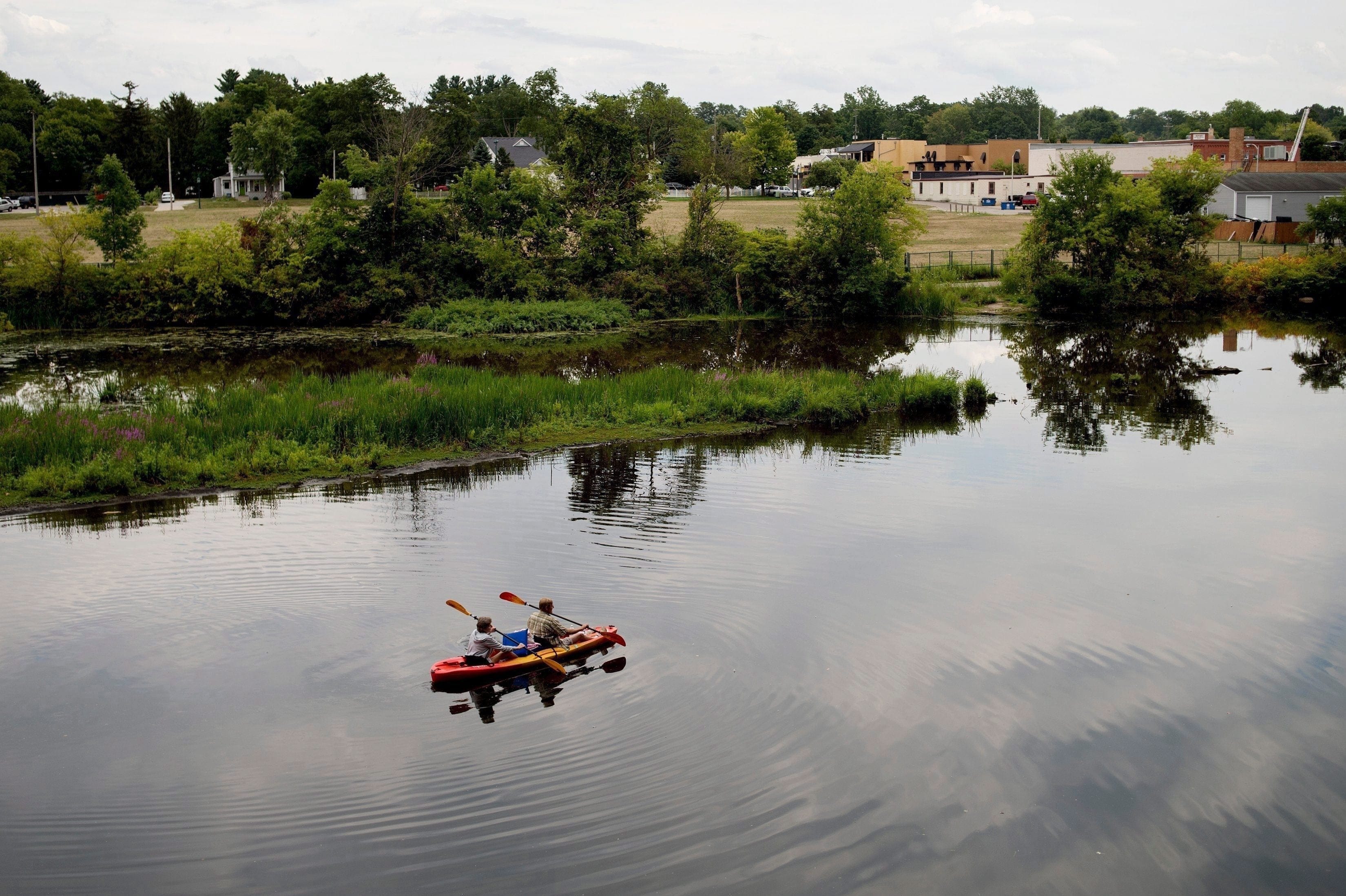 A couple kayak on the Rouge River adjacent to where Wolverine World Wide's tannery once stood, in Rockford, Mich. The Michigan Department of Environmental Quality is investigating the connection between old waste drums in the area and an old Wolverine World Wide tannery waste dump nearby. (Neil Blake /The Grand Rapids Press via AP)