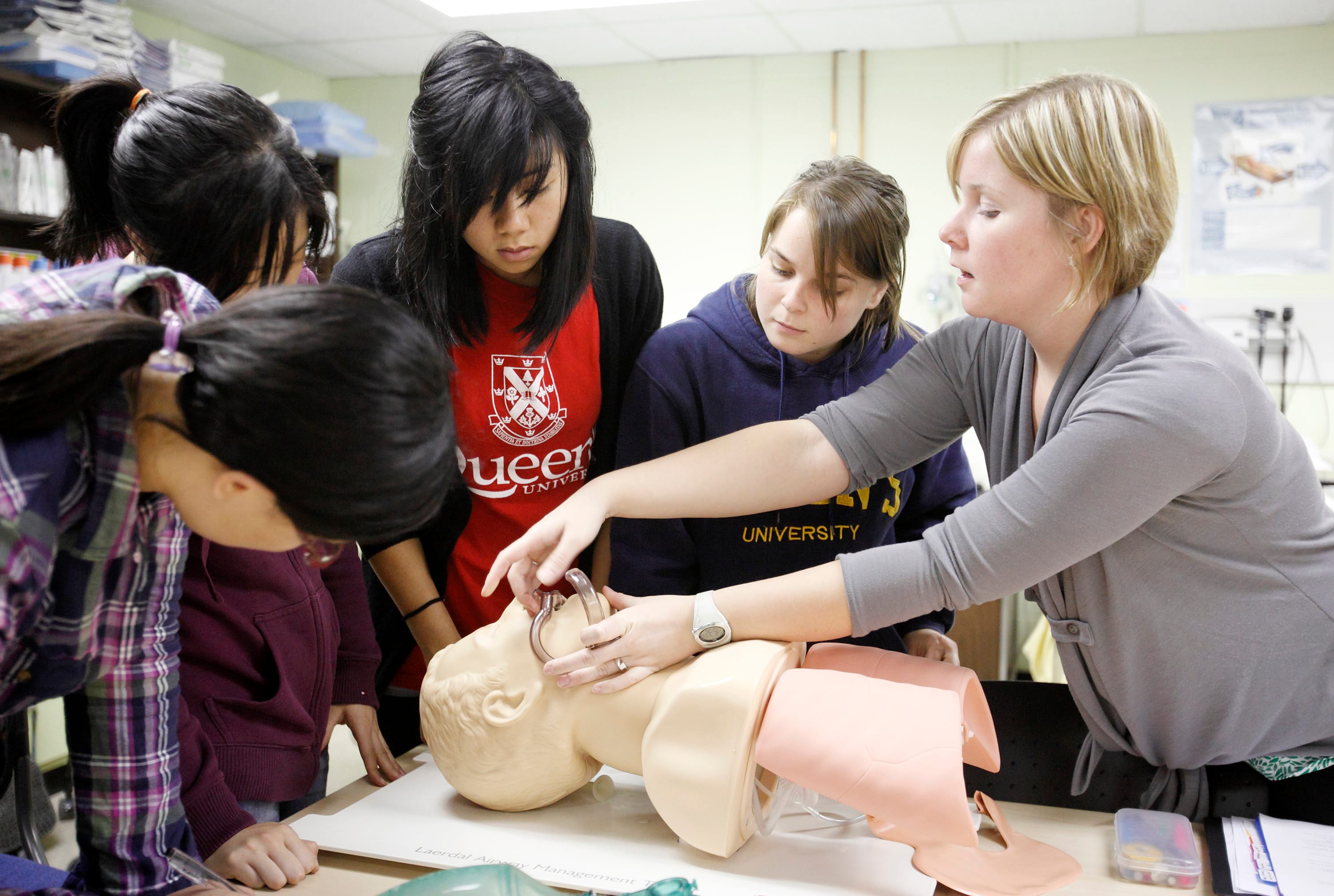 Instructor Lindsay Mossey, 25, (right) demonstrates how to insert a nasal airway to medical and nursing students Haitong Zhang (l), Rosaline Lai (2nd left) and Josephine Poon (m) (girl in blue queen's shirt - declined to be named) during a basic airway management lab faculty of health sciences' Patient Simulation Lab at Queen's University in Kingston. (Photograph by Yvonne Berg)